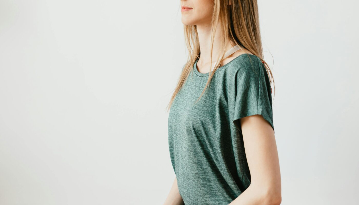 Side view of young slim female in sportswear sitting in Virasana pose with closed eyes while practicing yoga at home