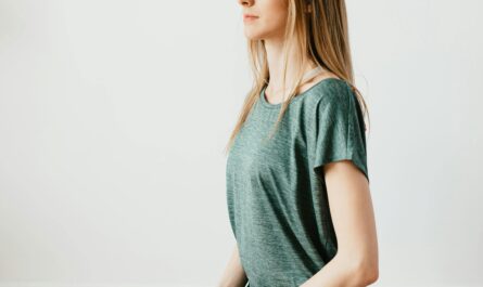 Side view of young slim female in sportswear sitting in Virasana pose with closed eyes while practicing yoga at home