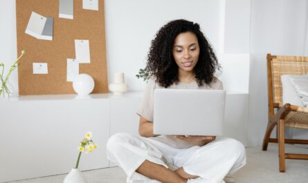 Young woman with curly hair working on her laptop in a cozy home setting, exuding confidence and focus.